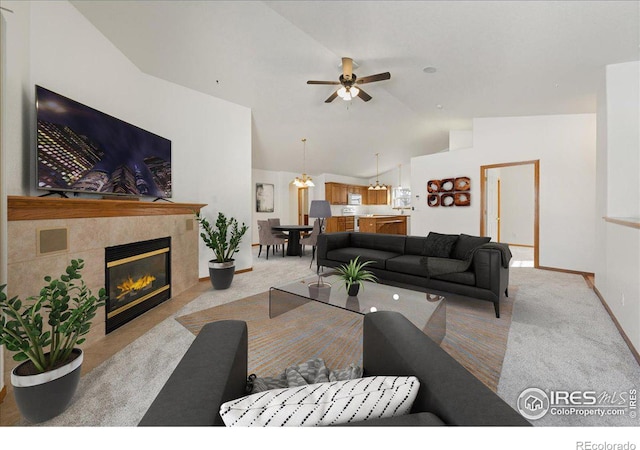 living room with light carpet, a tiled fireplace, lofted ceiling, and a ceiling fan