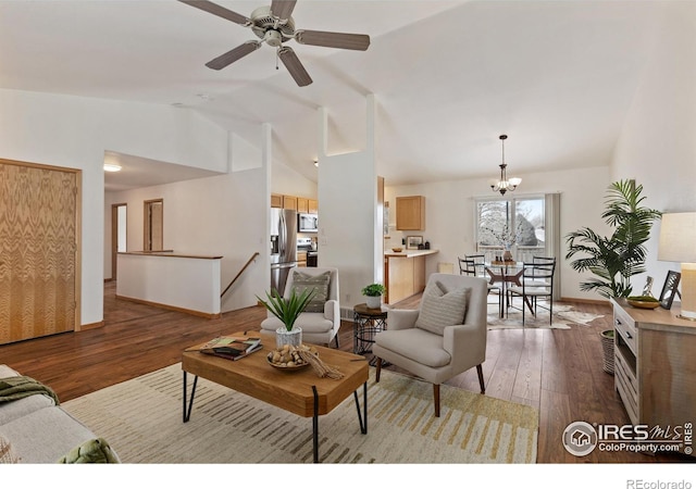 living area featuring dark wood-type flooring, lofted ceiling, baseboards, and ceiling fan with notable chandelier