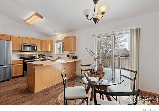 kitchen featuring lofted ceiling, light countertops, hanging light fixtures, appliances with stainless steel finishes, and a peninsula