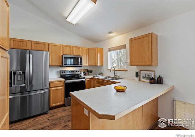 kitchen with lofted ceiling, stainless steel appliances, a peninsula, a sink, and light countertops