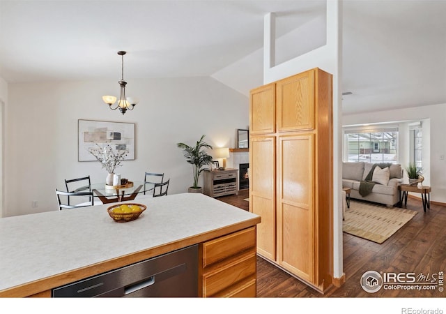 kitchen featuring lofted ceiling, dark wood-type flooring, light countertops, light brown cabinetry, and pendant lighting