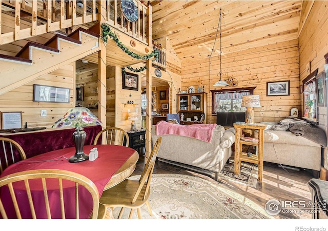 dining room with wood ceiling, wood finished floors, stairs, wood walls, and high vaulted ceiling