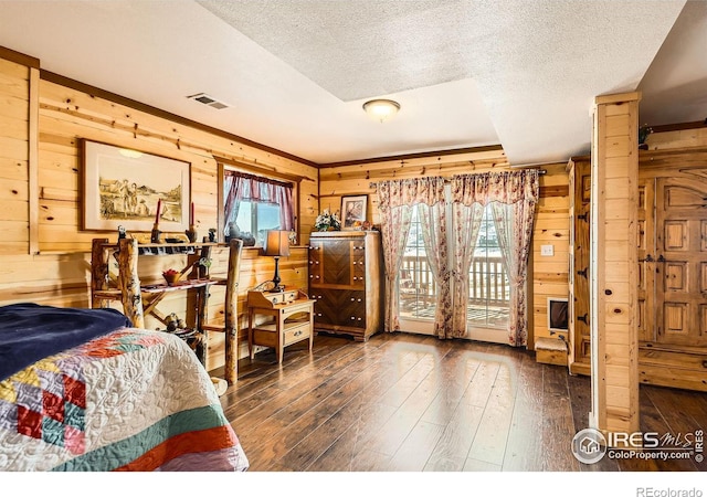 bedroom with dark wood-style floors, access to exterior, visible vents, and wooden walls