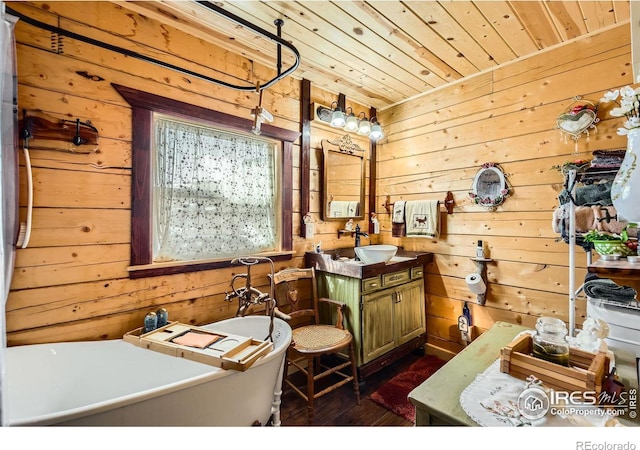 bathroom featuring wood walls, wood ceiling, wood finished floors, vanity, and a freestanding tub