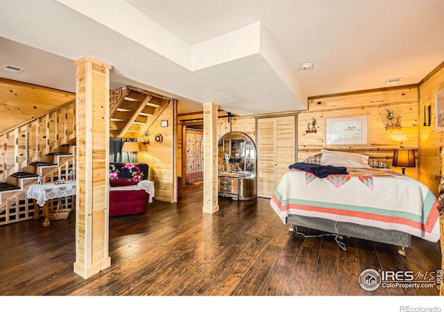 bedroom featuring dark wood-style floors, wood walls, and visible vents