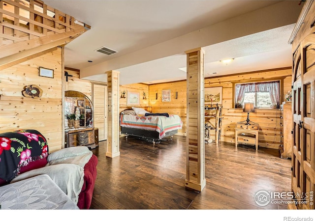 bedroom featuring wood walls, dark wood-style floors, and visible vents