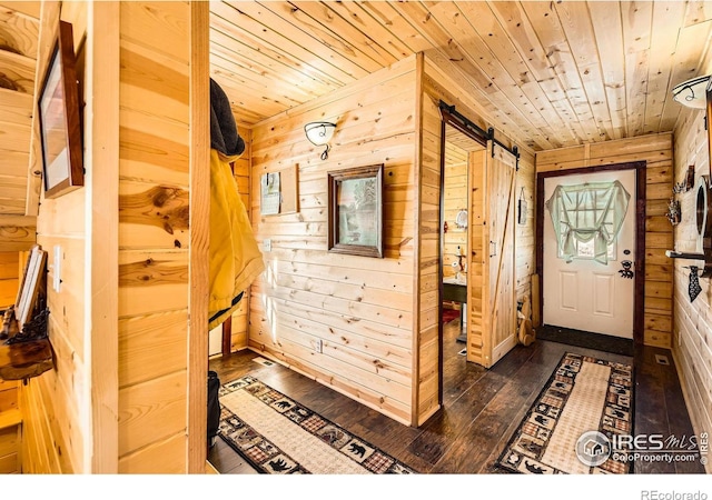 corridor featuring dark wood-style floors, wood ceiling, wooden walls, and a barn door