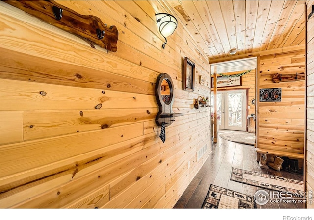 hall with visible vents, wood ceiling, wood finished floors, french doors, and wood walls