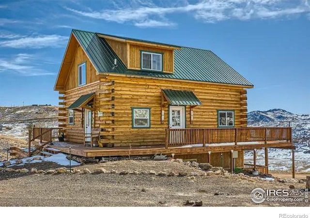 exterior space with metal roof, log exterior, a standing seam roof, and a deck with mountain view