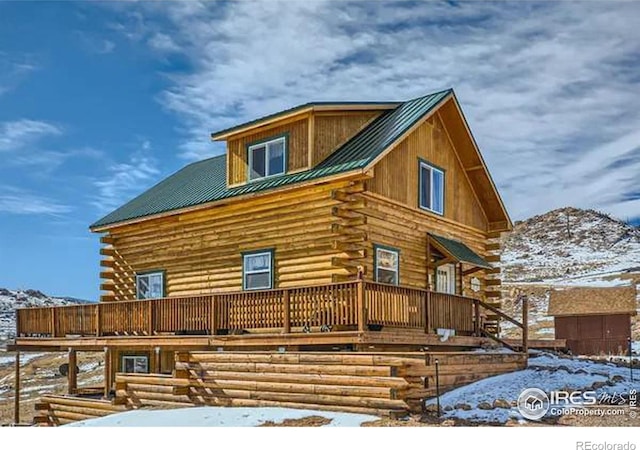 exterior space with metal roof, log exterior, and a wooden deck