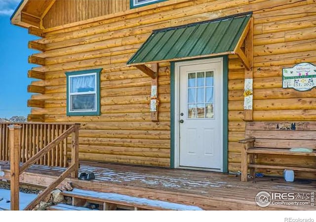 entrance to property featuring metal roof and log exterior