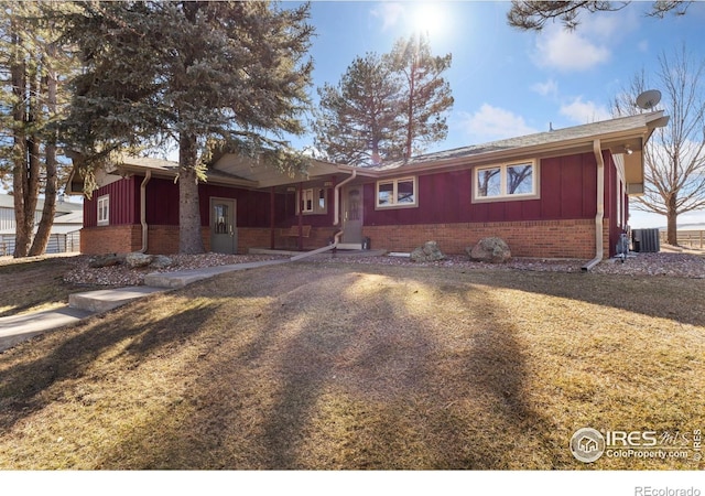 single story home with board and batten siding, brick siding, a front lawn, and central air condition unit