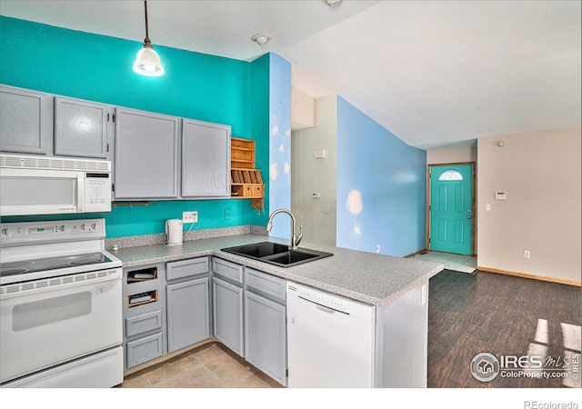 kitchen featuring white appliances, a peninsula, light countertops, pendant lighting, and a sink