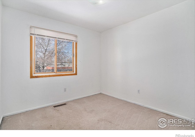 spare room with carpet, visible vents, and baseboards