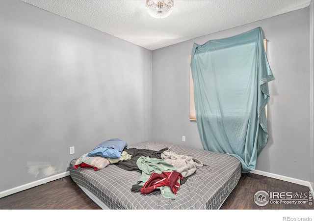 bedroom featuring dark wood-style flooring, a textured ceiling, and baseboards