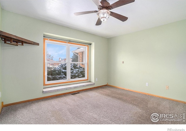 carpeted spare room with visible vents, baseboards, and a ceiling fan