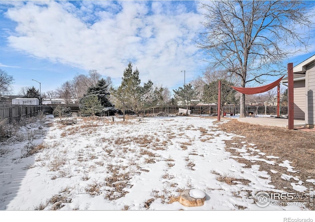 yard layered in snow featuring a carport and a fenced backyard