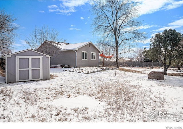 snow covered back of property with an outbuilding and a storage unit