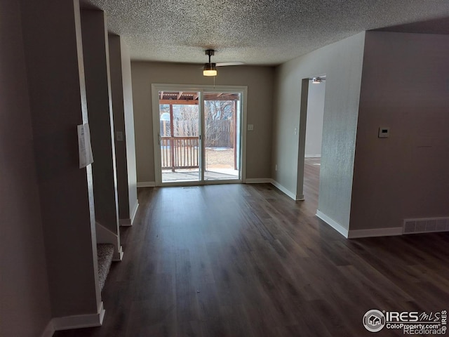 unfurnished dining area featuring baseboards, a textured ceiling, visible vents, and dark wood-style flooring