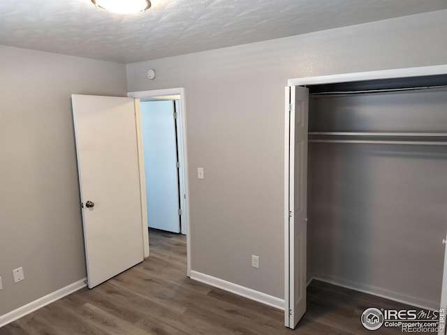 unfurnished bedroom featuring a closet, baseboards, and wood finished floors