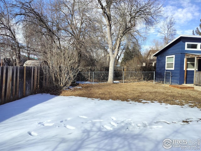 yard layered in snow featuring a fenced backyard