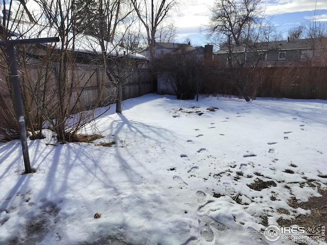 yard covered in snow featuring fence