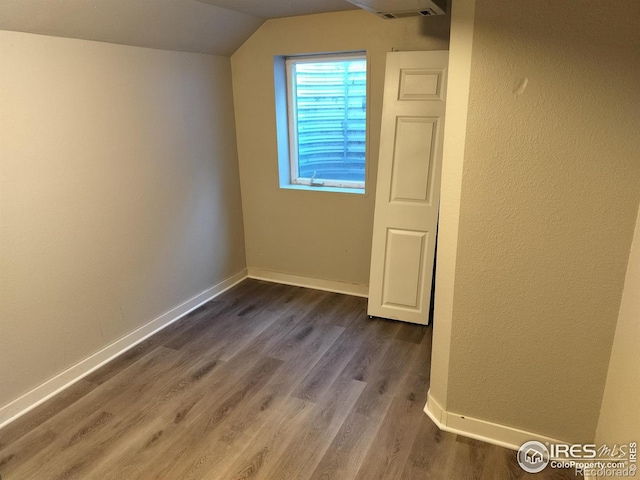 bonus room with dark wood-style floors, lofted ceiling, and baseboards