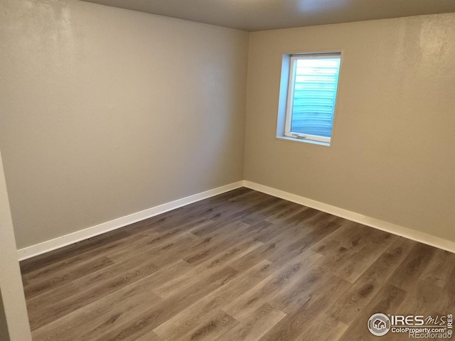 empty room with dark wood-style floors and baseboards