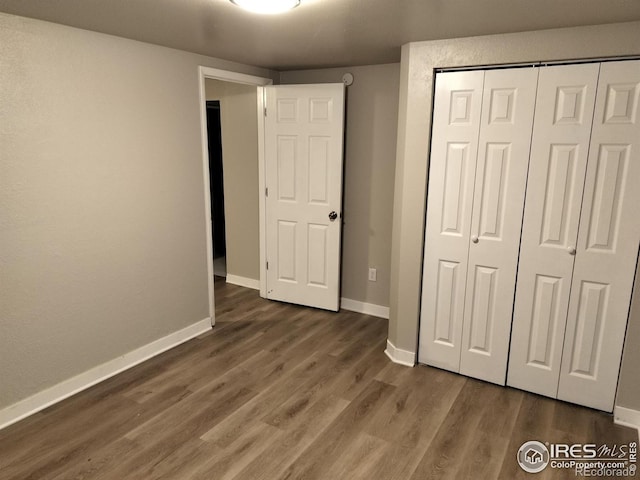 unfurnished bedroom featuring a closet, baseboards, and wood finished floors