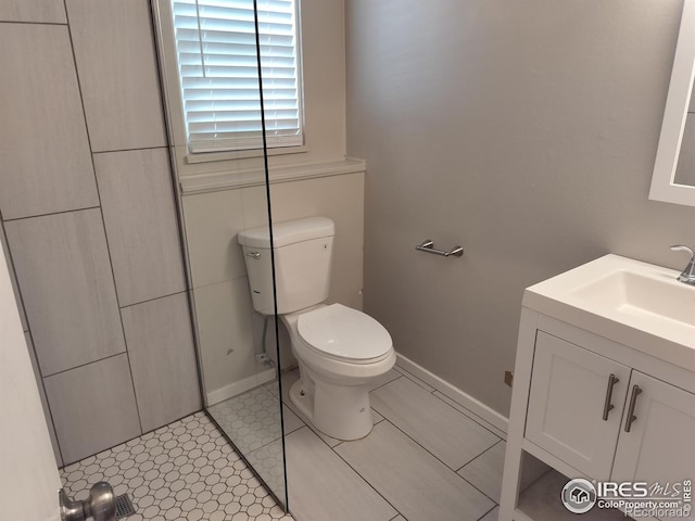 full bathroom with baseboards, vanity, and toilet