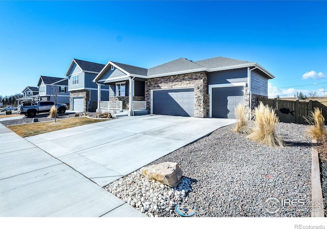 view of front of property with a garage, covered porch, fence, stone siding, and concrete driveway