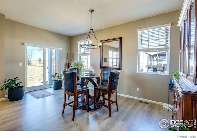 dining area featuring light wood finished floors, visible vents, a chandelier, and baseboards