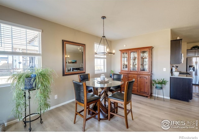 dining room with baseboards, light wood-style flooring, and an inviting chandelier