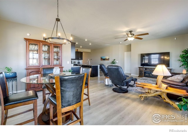 dining room featuring ceiling fan with notable chandelier and light wood-type flooring