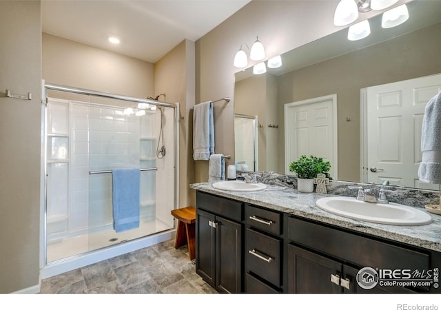 full bath featuring double vanity, a stall shower, and a sink