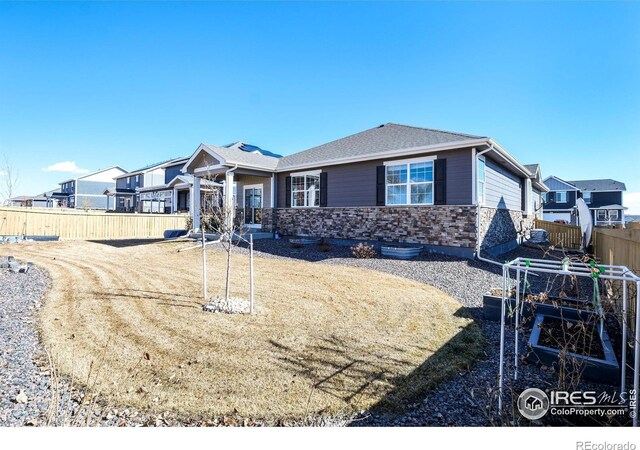 view of front facade with a residential view, stone siding, and fence