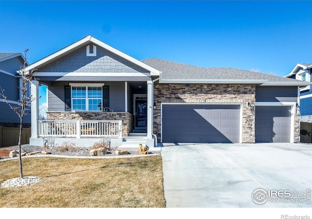 view of front facade with an attached garage, stone siding, a porch, and concrete driveway