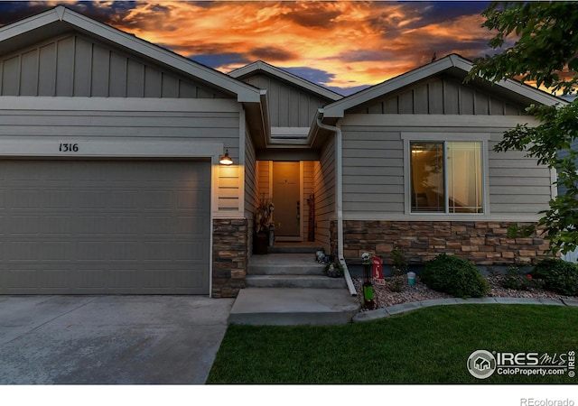 view of front of home with board and batten siding, stone siding, an attached garage, and concrete driveway