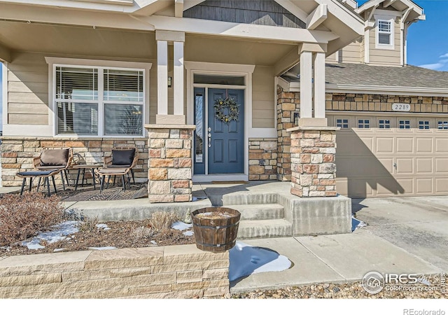 property entrance with a porch, stone siding, and an attached garage