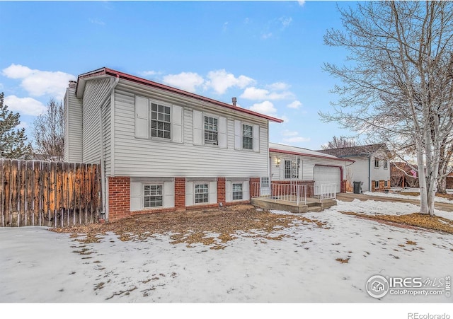 split level home with a garage, brick siding, and fence