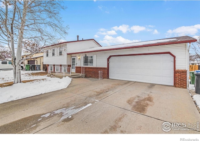 tri-level home featuring a garage, concrete driveway, and brick siding