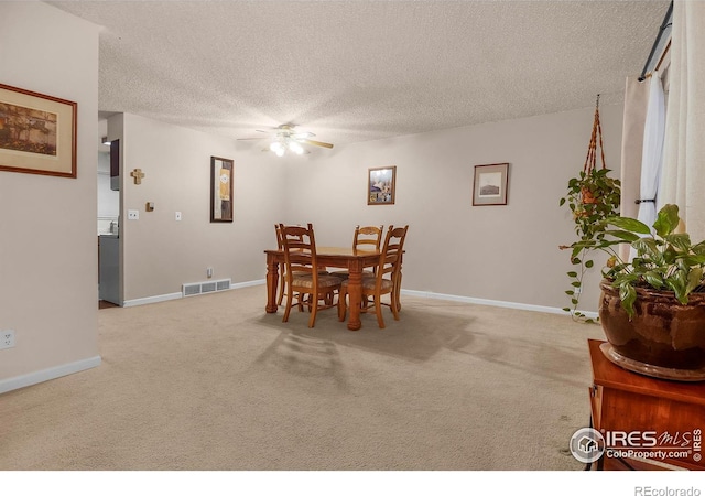 dining room featuring light carpet, ceiling fan, a textured ceiling, and visible vents