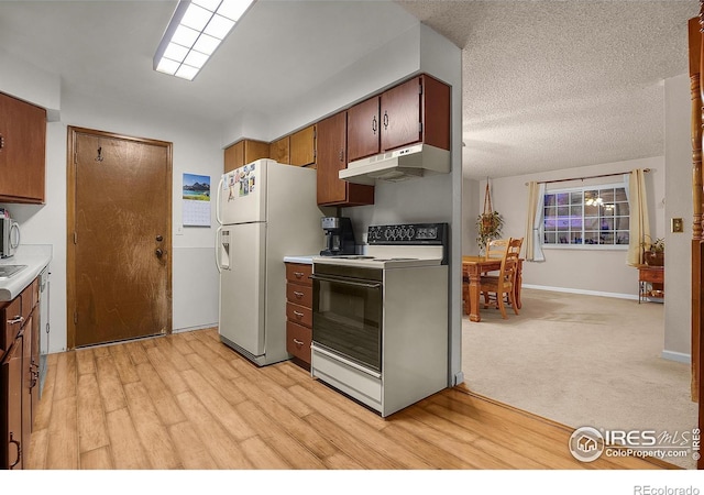 kitchen featuring light countertops, white appliances, light wood-type flooring, and under cabinet range hood