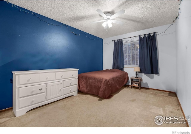 bedroom with ceiling fan, baseboards, a textured ceiling, and light colored carpet