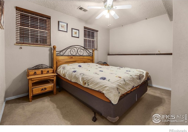 carpeted bedroom with a textured ceiling, ceiling fan, visible vents, and baseboards