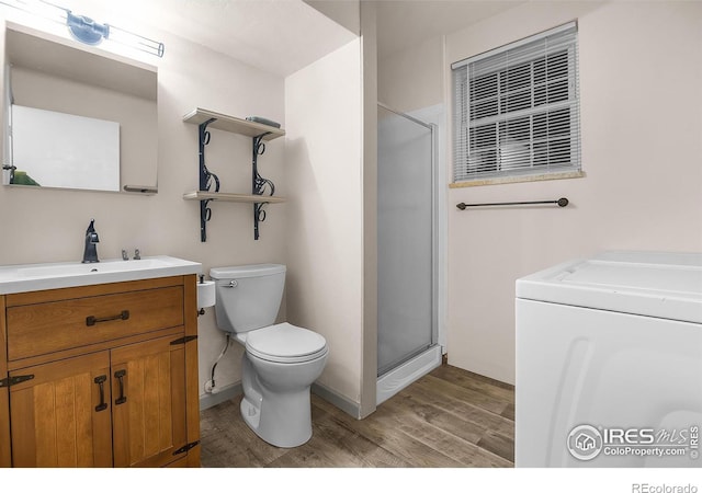 full bath featuring toilet, wood finished floors, vanity, a shower stall, and washer / clothes dryer