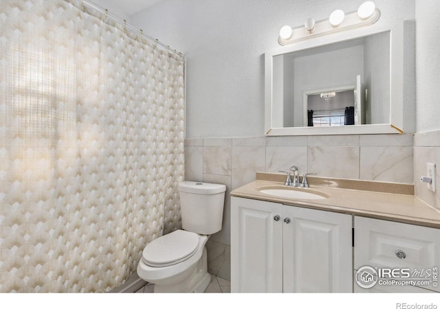 bathroom with toilet, tile walls, and vanity