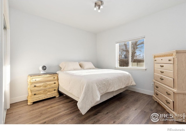 bedroom with dark wood finished floors and baseboards