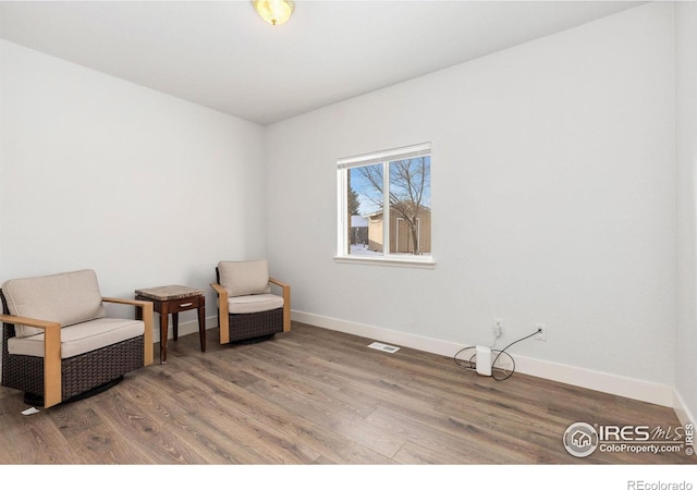 sitting room featuring visible vents, baseboards, and wood finished floors