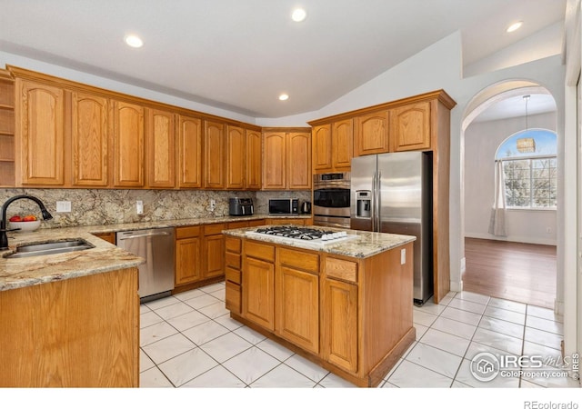 kitchen featuring decorative backsplash, lofted ceiling, brown cabinets, stainless steel appliances, and a sink